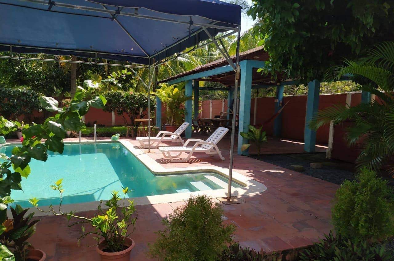 Piscina con dos sillas reclinables y el hamaquero al fondo
